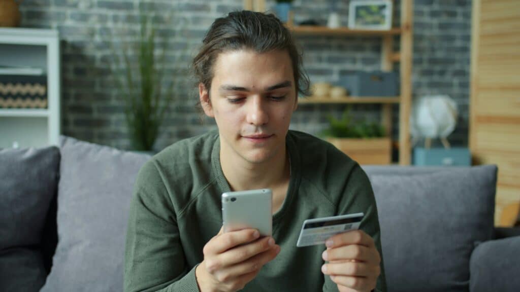 Pessoa analisando operação financeira no celular com cartão bancário